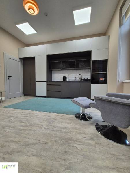 Küche in einer Einzimmerwohnung mit Holzboden und einem bequemen Sessel.