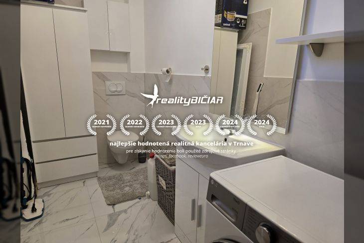 Badezimmer in einer Ferienwohnung mit Waschmaschine und Marmordekor an den Wänden.