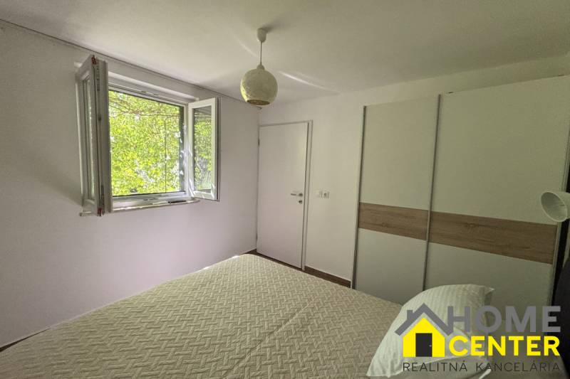 Helles Schlafzimmer mit Fenster, weißer Wand und Schrank in einem Einfamilienhaus.