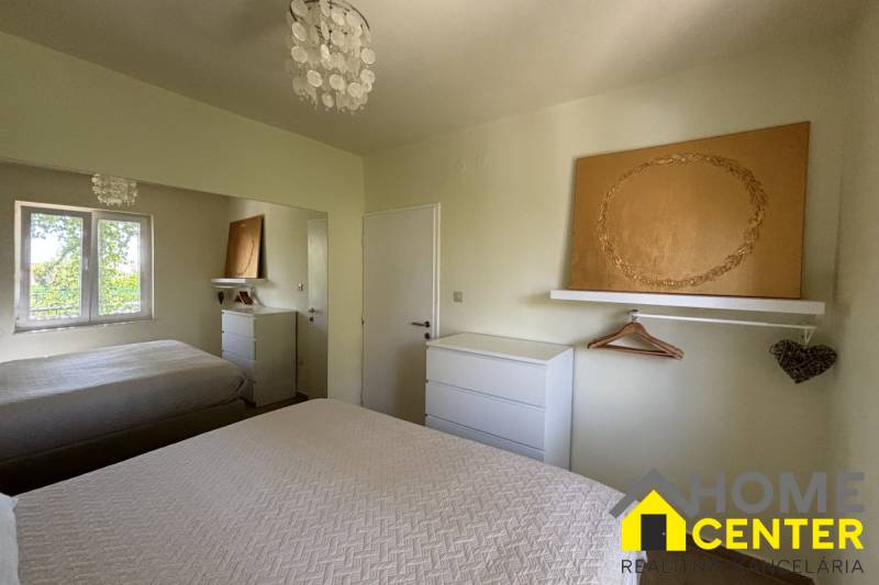 Schlafzimmer in einem Einfamilienhaus mit weißen Möbeln, Spiegel und texturierten Bettüberwürfen.