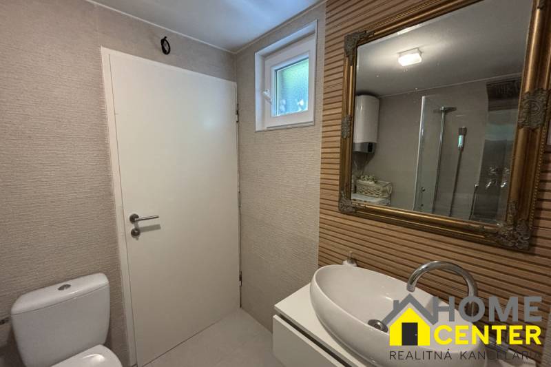 Badezimmer in einem Einfamilienhaus mit Waschbecken, Spiegel und Duschkabine.