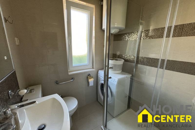 Badezimmer in einem Einfamilienhaus mit Dusche, Waschmaschine und Fenster.