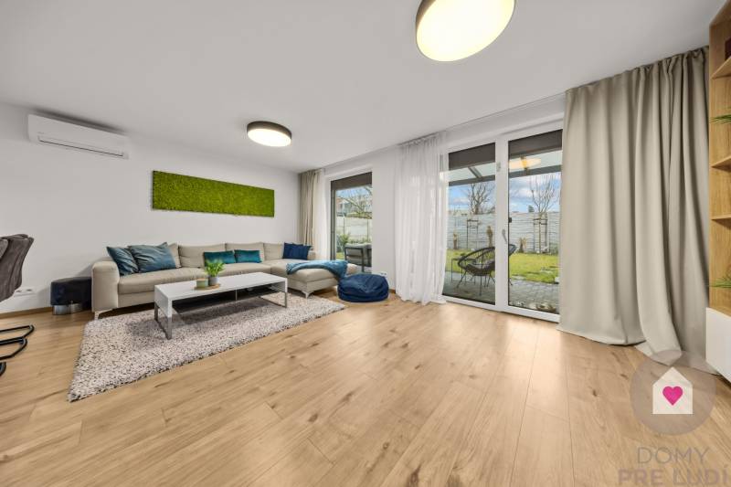 Wohnzimmer mit Sofa, Glastüren und Holzboden in einer 4-Zimmer-Wohnung.