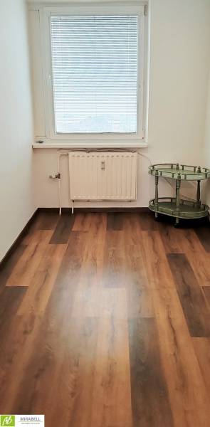 Ein Zimmer mit einem Holzboden und einem grünen Tisch, eine 3-Zimmer-Wohnung.