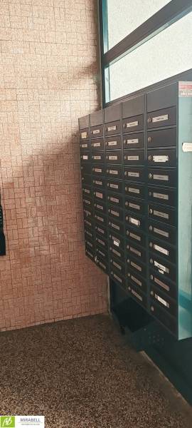 Briefkästen im Flur einer 3-Zimmer-Wohnung, Wand mit Ziegelverkleidung, Böden mit Steindekor.