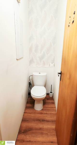 Toilette in einer 3-Zimmer-Wohnung mit weißen Wänden und einem Boden in Holzoptik.