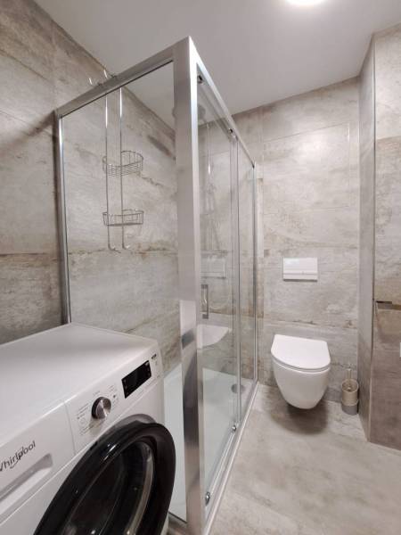 Badezimmer mit Waschmaschine, Duschkabine und Hänge-WC in einer 2-Zimmer-Wohnung.