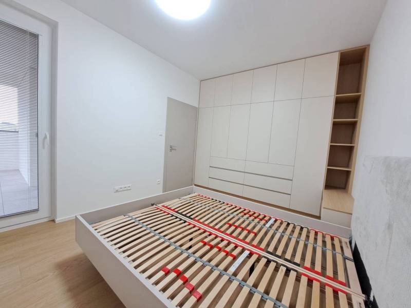 Schlafzimmer mit Holzboden, Einbauschrank und Bett in einer 2-Zimmer-Wohnung.