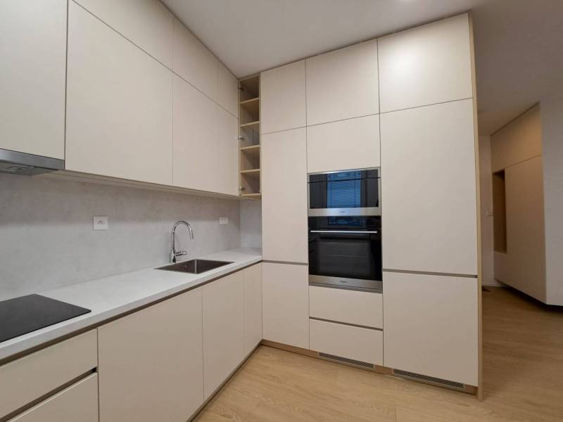 Küche in einer 2-Zimmer-Wohnung mit Holzboden, hellen Schränken und eingebautem Ofen.