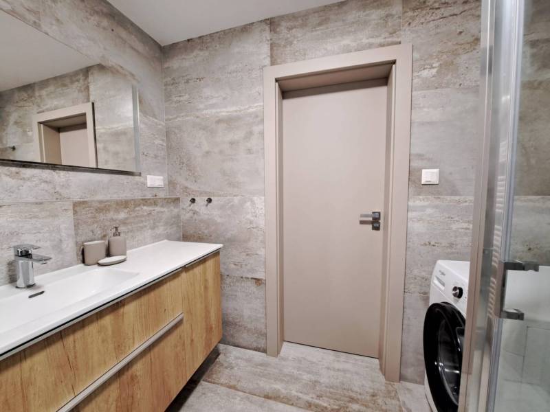 Badezimmer mit Waschbecken und Boden in Holzoptik in einer 2-Zimmer-Wohnung.