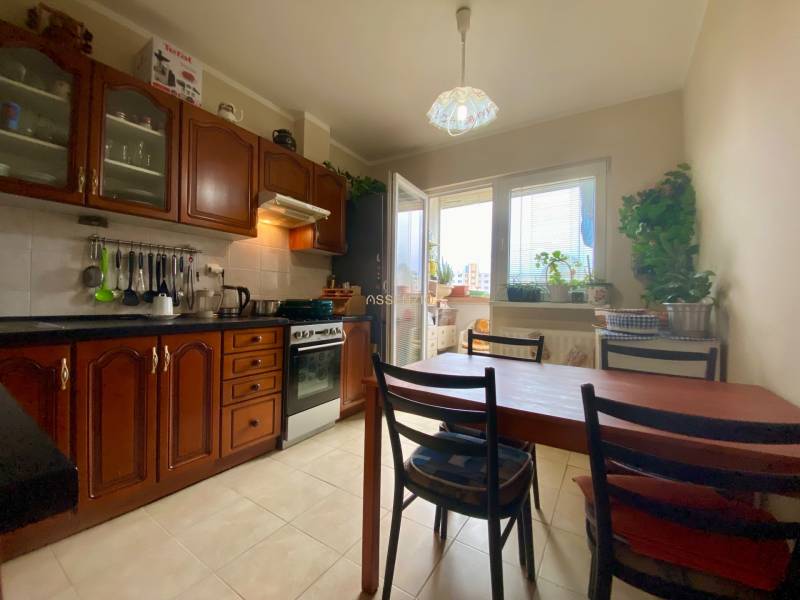 Küche in einer 3-Zimmer-Wohnung mit Holzschränken, Esstisch und Fenster zum Balkon.