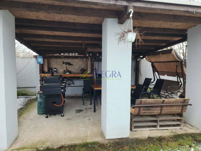 Ein Einfamilienhaus in Tornyosnémeti mit überdachter Terrasse, Grill, Schaukelbank und Essbereich.