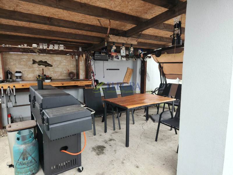 Überdachte Sitzecke in einem Einfamilienhaus in Tornyosnémeti mit Grill und Tisch.