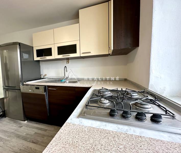 Küche in einer 2-Zimmer-Wohnung mit einem Gasherd und einem Boden in Holzoptik.