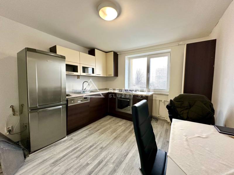 Küche in einer 2-Zimmer-Wohnung mit Holzboden und einem Tisch mit Stühlen.