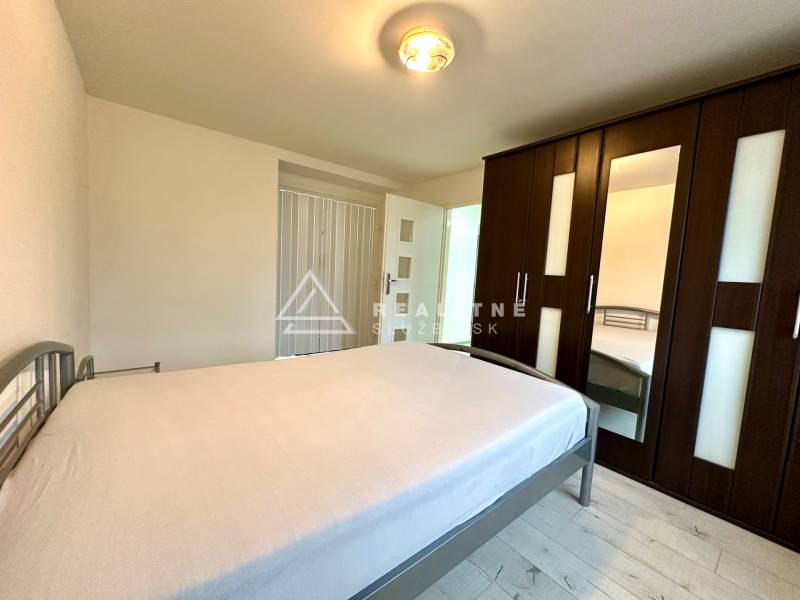 Schlafzimmer in einer 2-Zimmer-Wohnung mit Bett, Schrank und Boden mit Holzdekor.