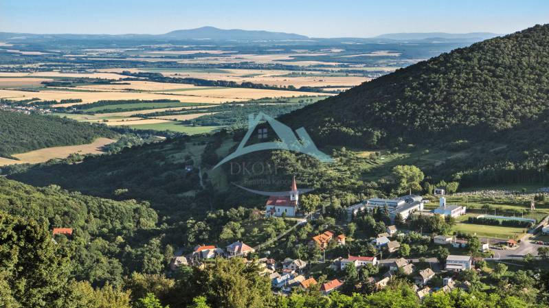 Panoramablick auf ein Dorf im Tal, umgeben von Wäldern und Feldern. Grundstücke geeignet zum Wohnen.
