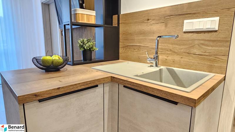 Küchenzeile in einer Einzimmerwohnung mit Spüle und Boden in Holzoptik.