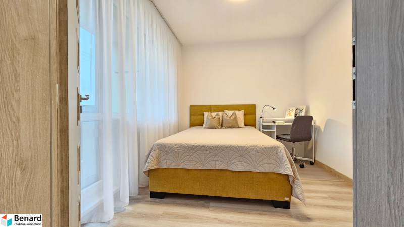 Schlafzimmer in einer Einzimmerwohnung mit Bett, Schreibtisch und Holzboden.