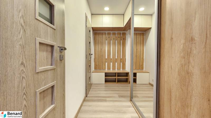 Innenraum einer Einzimmerwohnung mit Holzboden, Schränken und einer Garderobenwand.