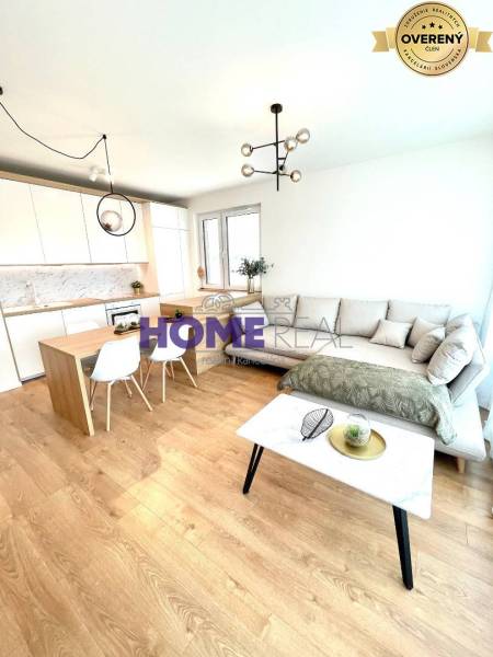 Wohnzimmer mit Küche in einer 3-Zimmer-Wohnung, helle Couch, Boden mit Holzdekor.