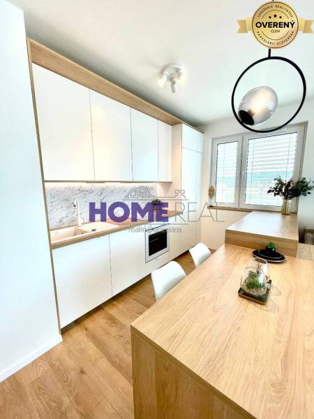 Küche in einer 3-Zimmer-Wohnung mit weißen Schränken und einem Boden in Holzoptik.