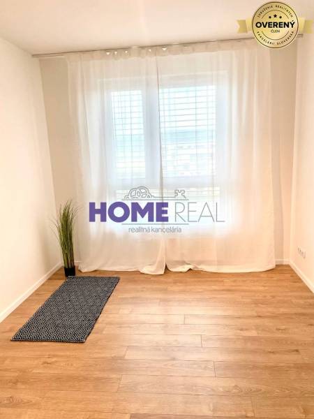 Ein Zimmer mit einem Holzboden und weißen Vorhängen in einer 3-Zimmer-Wohnung.