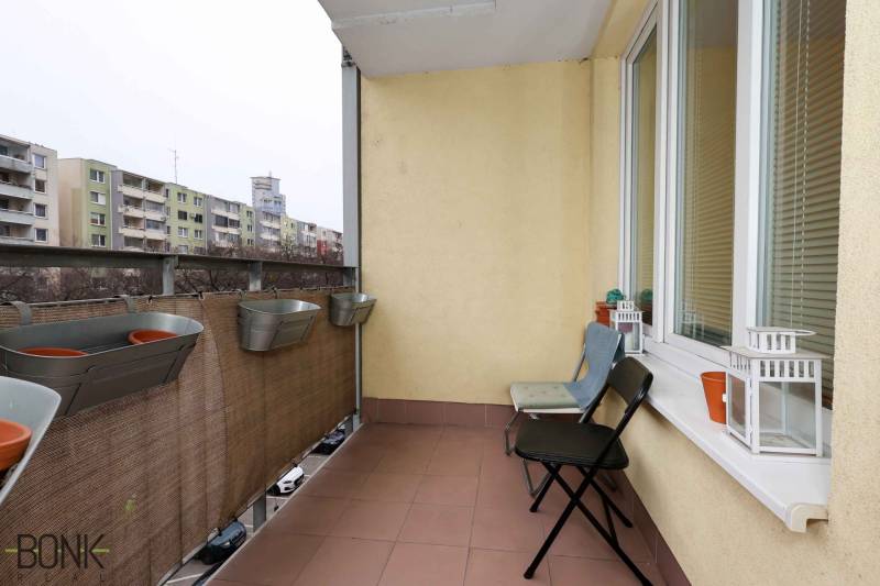 Balkon einer 2-Zimmer-Wohnung in der Jégeho 8 in Bratislava-Ružinov mit Blumenkästen und Stühlen.