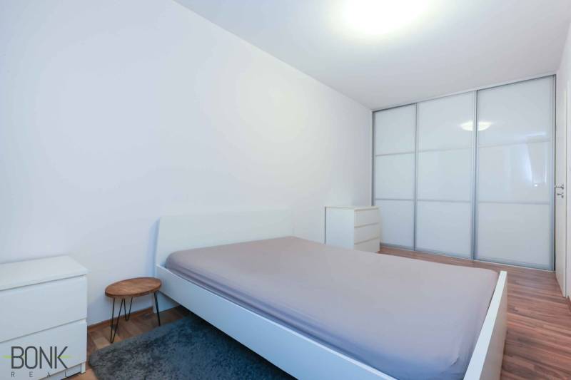 Schlafzimmer in einer 2-Zimmer-Wohnung mit großem Einbauschrank und Boden in Holzoptik.