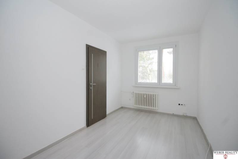 Ein Zimmer in einer 3-Zimmer-Wohnung mit weißen Wänden, einem Boden in Holzoptik und einem Fenster.