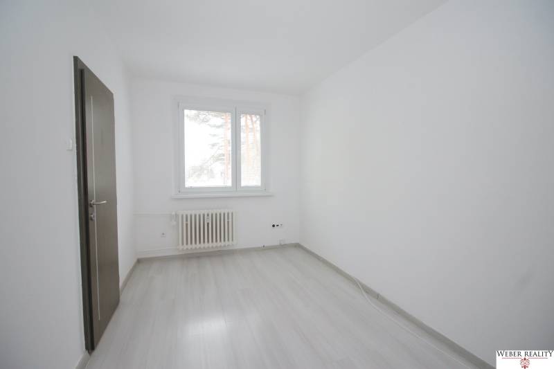 Ein Zimmer mit Fenster, Heizkörper und Boden in Holzoptik in einer 3-Zimmer-Wohnung.