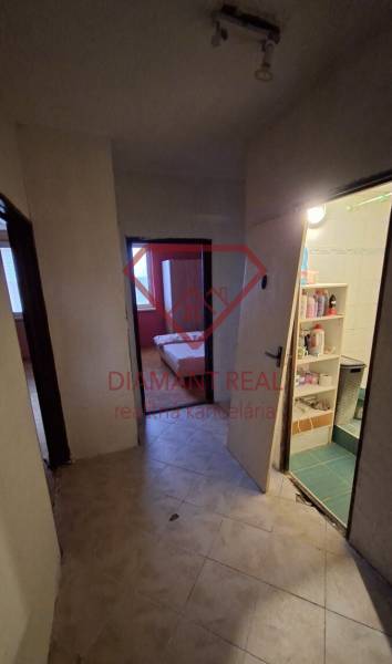 Flur in einer 3-Zimmer-Wohnung mit Zugang zum Badezimmer und Zimmer, Boden mit Holzdekor.