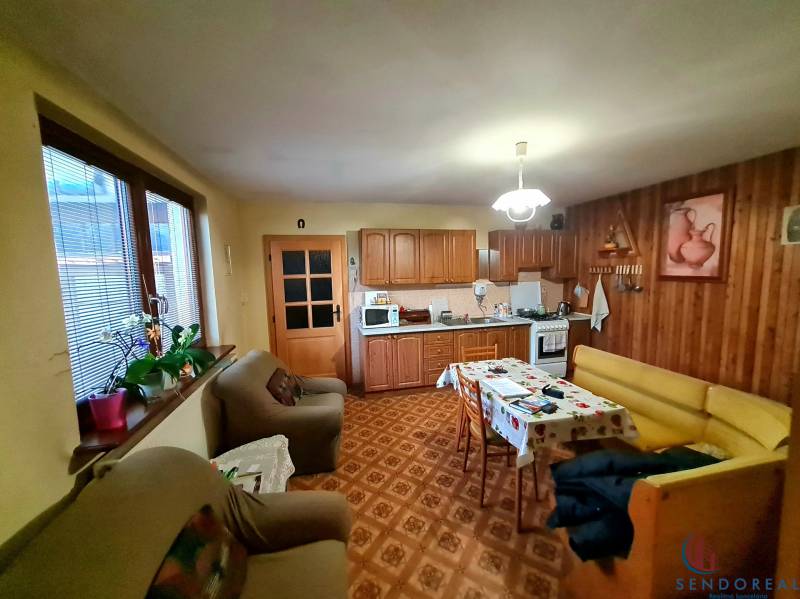 Küche in einem Einfamilienhaus mit Holzdekor, Sitzgarnitur und Esstisch.