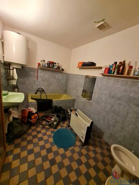 Badezimmer im Einfamilienhaus mit Badewanne, Waschbecken, Regalen und Heizkörper.