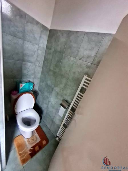 Badezimmer mit Toilette in einem Einfamilienhaus, gefliest mit grünlichen Fliesen.