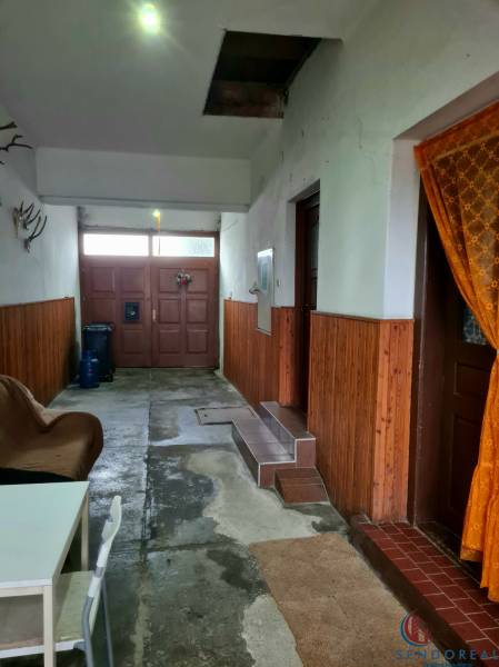 Innenraum eines Einfamilienhauses mit Eingangstür, Stuhl und Wanddekorationen.