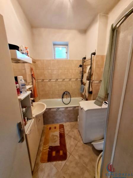 Badezimmer mit Badewanne, Waschbecken, Waschmaschine und Regalen in einem Einfamilienhaus.