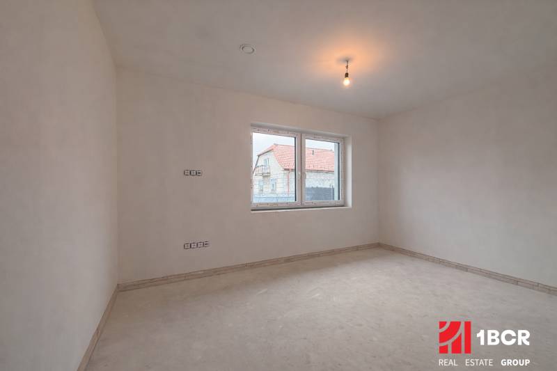 Ein geräumiges Zimmer in einem Einfamilienhaus mit einem Fenster mit Blick auf ein anderes Haus.