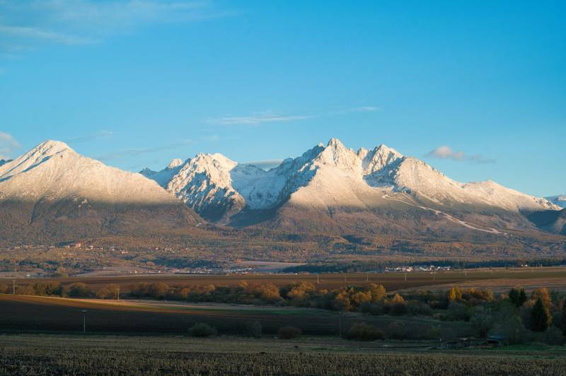 Schneebedeckte Gipfel, herbstliche Landschaft und landwirtschaftliche sowie forstwirtschaftliche Flächen rund um Poprad.