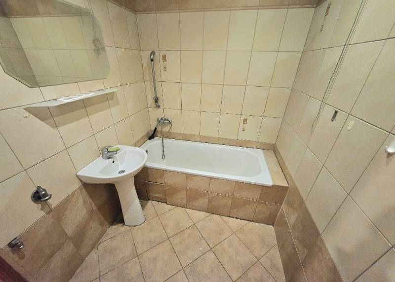 Badezimmer in einer 3-Zimmer-Wohnung mit Badewanne, Waschbecken und beigefarbenen Keramikfliesen.