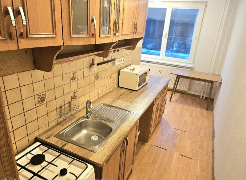 Küche mit Holzboden und Fenster, Teil einer 3-Zimmer-Wohnung.