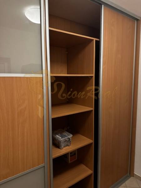 Ein Kleiderschrank mit Schiebetüren und Regalen in einer Einzimmerwohnung.