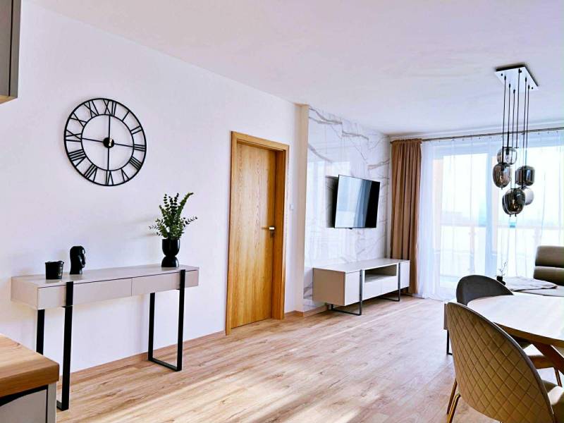 Wohnzimmer in einer 3-Zimmer-Wohnung mit Holzboden, Tisch und Fernseher.