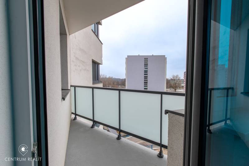 Balkon in einer 2-Zimmer-Wohnung mit Blick auf die umliegenden Gebäude durch ein Glasgeländer.