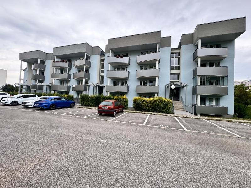 Ein Wohnhaus mit grauen Balkonen in Halalovka in Trenčín mit Parkplätzen.