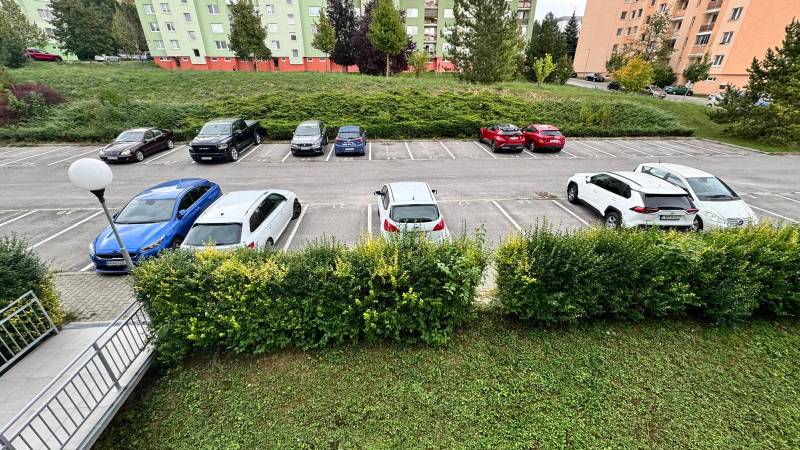 Parkplatz auf Halalovka in Trenčín mit Autos im Hintergrund von Wohnhäusern.