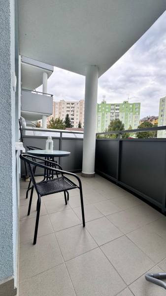 Der Balkon einer 2-Zimmer-Wohnung in Halalovka in Trenčín mit Tisch und Stühlen, Blick auf die Plattenbauten.