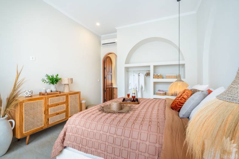 Helles Schlafzimmer in einer Villa mit natürlichen Dekorationen, sanfter Beleuchtung und einem bequemen Bett.