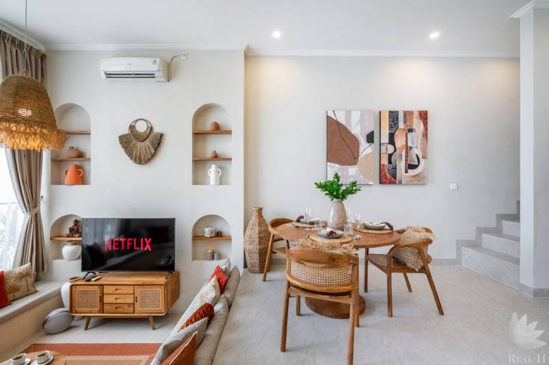 Wohnzimmer der Villa mit Fernseher, Esstisch und dekorativen Elementen an den Wänden.