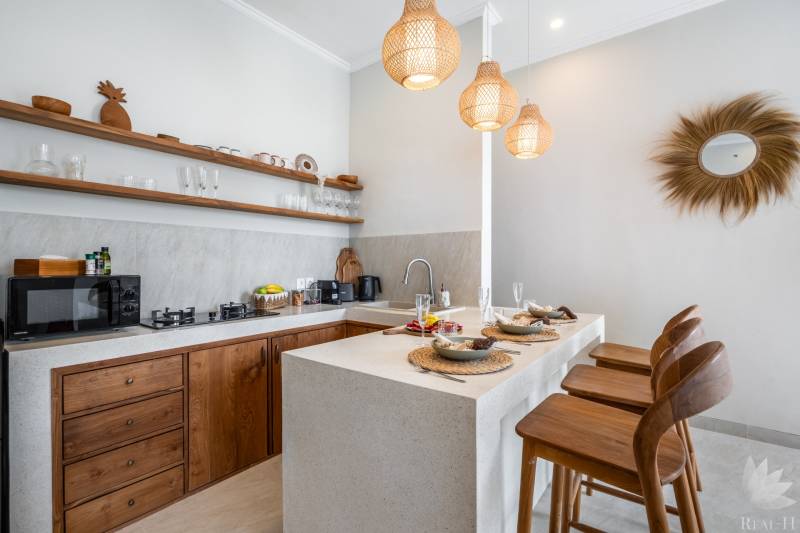 Die Küche der Villa mit stilvollen Holzelementen, Barhockern und Hängelampen.